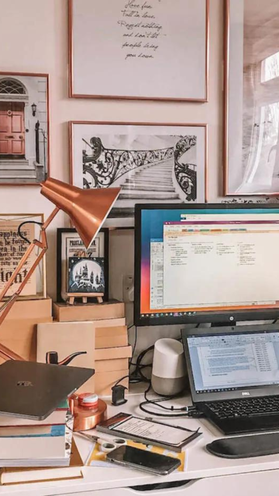 A messy but aesthetic desk with a laptop and a large monitor behind it  