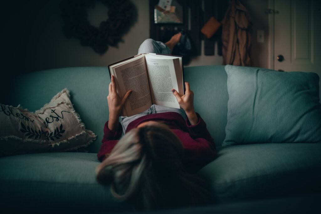 Girl reading book upside down on a couch 